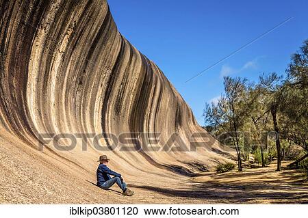 Stock Image - "Man resting at the bottom of Wave Rock, near Hyden, Western Australia, Australia, Oceania". Fotosearch