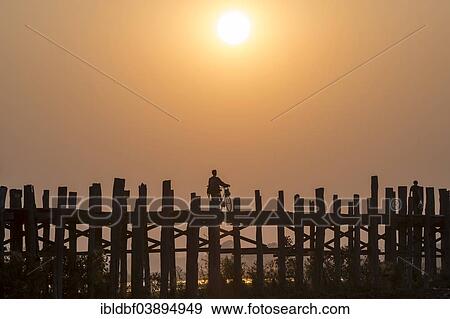 "Man riding a bike on a teak bridge, U Bein Bridge across Thaungthaman Lake at sunset, Amarapura, Mandalay Division, Myanmar, Asia" View Large Photo Image Stock Photo - "Man riding a bike on a teak bridge, U Bein Bridge across Thaungthaman Lake at sunset, Amarapura, Mandalay Division, Myanmar, Asia". Fotosearch