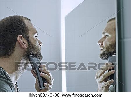 Stock Photo - Man shaving his beard in front of a mirror. Fotosearch