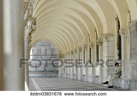 Stock Photo - "Man sitting and reading in the colonnade at Doge's Palace, Palazzo Ducale, Venice, Veneto, Italy, Europe". Fotosearch