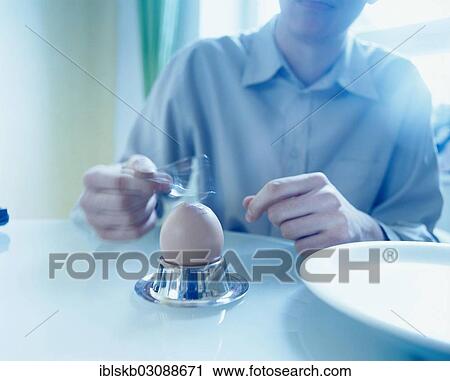 Man sitting at a table and tapping a boiled egg with a spoon View Large Photo Image Stock Image - Man sitting at a table and tapping a boiled egg with a spoon. Fotosearch