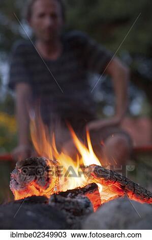 Man sitting behind a fire in a garden View Large Photo Image Stock Image - Man sitting behind a fire in a garden. Fotosearch