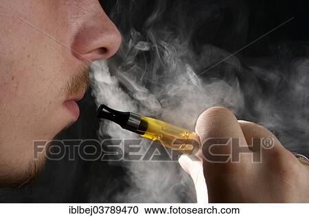 Stock Image - Man smoking an electronic cigarette and exhaling vapour. Fotosearch