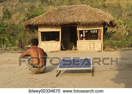"Man squatting in front of a straw hut, solar panel next to him for recharging, Boga Lake, Chittagong Hill Tracts, Ruma Bazar, Bangladesh, South Asia, Asia" View Large Photo Image Stock Image - "Man squatting in front of a straw hut, solar panel next to him for recharging, Boga Lake, Chittagong Hill Tracts, Ruma Bazar, Bangladesh, South Asia, Asia". Fotosearch