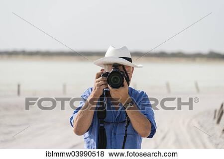 Stock Photo - "Man taking a photo, Etosha pan, salt pan, Etosha National Park, Namibia, Africa". Fotosearch