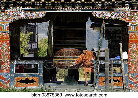 "Man turning the large prayer wheel in the town centre of Mongar, Mongar, Mongar District, Bhutan, Asia" View Large Photo Image Stock Photo - "Man turning the large prayer wheel in the town centre of Mongar, Mongar, Mongar District, Bhutan, Asia". Fotosearch