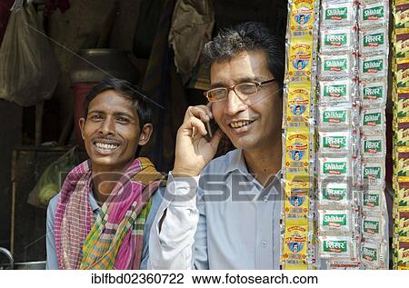 "Man using a mobile phone, another man smiling in the back, Kolkata, India, Asia" View Large Photo Image Stock Image - "Man using a mobile phone, another man smiling in the back, Kolkata, India, Asia". Fotosearch