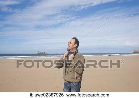 Stock Photograph - Man walking along the beach. Fotosearch