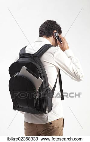 "Man wearing a backpack, from which an iPad is sticking out, talking on a mobile phone" View Large Photo Image Stock Photo - "Man wearing a backpack, from which an iPad is sticking out, talking on a mobile phone". Fotosearch