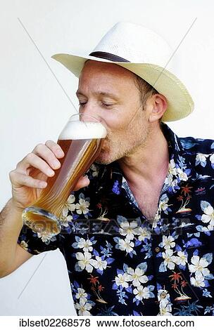 Man wearing a straw hat and a Hawaiian shirt drinking wheat beer View Large Photo Image Stock Photo - Man wearing a straw hat and a Hawaiian shirt drinking wheat beer. Fotosearch