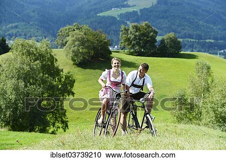 "Man wearing leather pants and a woman wearing a dirndl on old bicycles within a natural landscape, Igls, Innsbruck, Tyrol, Austria, Europe" View Large Photo Image Stock Image - "Man wearing leather pants and a woman wearing a dirndl on old bicycles within a natural landscape, Igls, Innsbruck, Tyrol, Austria, Europe". Fotosearch