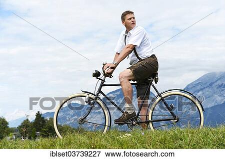 Stock Photo - "Man wearing leather pants on an old bicycle, Igls, Innsbruck, Tyrol, Austria, Europe". Fotosearch