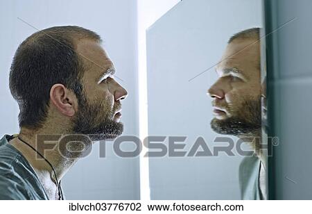 Man with a beard looking into a mirror View Large Photo Image Stock Image - Man with a beard looking into a mirror. Fotosearch