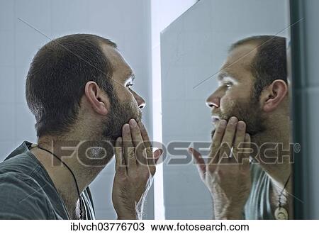 Man with a beard looking into a mirror View Large Photo Image Stock Image - Man with a beard looking into a mirror. Fotosearch