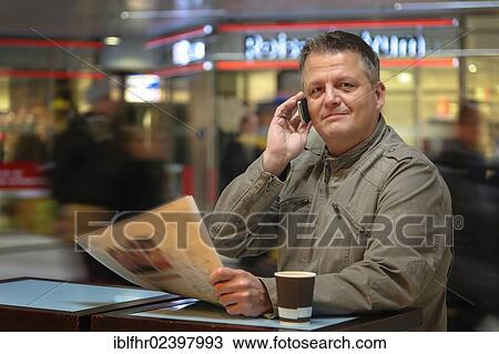 "Man with a newspaper and a mobile phone in a shopping mall, Duesseldorf, North Rhine-Westphalia, Germany, Europe" View Large Photo Image Stock Image - "Man with a newspaper and a mobile phone in a shopping mall, Duesseldorf, North Rhine-Westphalia, Germany, Europe". Fotosearch