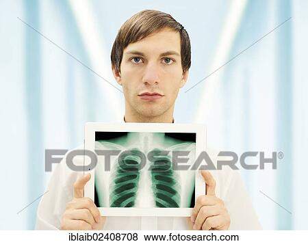 Stock Photo - Man with a serious face holding an iPad with a radiographic image of a lung. Fotosearch