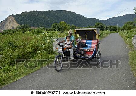 Stock Image - "Man with child on motorcycle Rick Shah, Lam Rukam, Subdistrict Rozma, Aceh, Indonesia, Asia". Fotosearch