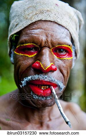"Man with colourful face paint smoking a cigarette is celebrating at the traditional Sing Sing gathering in the highlands, Paya, Papua New Guinea, Oceania" View Large Photo Image Stock Image - "Man with colourful face paint smoking a cigarette is celebrating at the traditional Sing Sing gathering in the highlands, Paya, Papua New Guinea, Oceania". Fotosearch