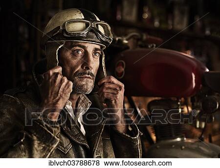 Man with old leather jacket putting on an old motorcycle helmet View Large Photo Image Stock Photo - Man with old leather jacket putting on an old motorcycle helmet. Fotosearch