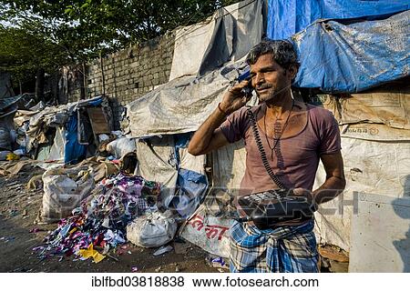 Stock Photo - "Man working at Dharavi Slum, using a telephone, Mumbai, Maharashtra, India, Asia". Fotosearch