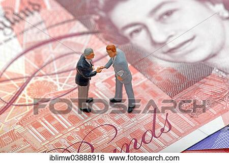 "Managers shaking hands, miniature figurines on top of a British Pound Sterling banknote, symbolic image for business" View Large Photo Image Stock Photograph - "Managers shaking hands, miniature figurines on top of a British Pound Sterling banknote, symbolic image for business". Fotosearch