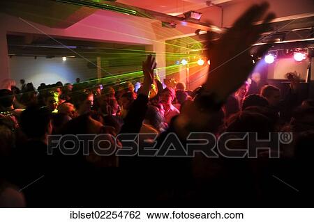 Stock Image - "Many young people on the dance floor at a nightclub or discotheque, holding hands in the air". Fotosearch