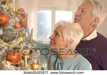 Stock Image - Mature couple decorating a Christmas tree. Fotosearch