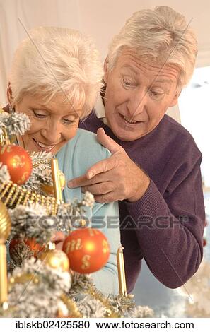Stock Image - Mature couple decorating a Christmas tree. Fotosearch
