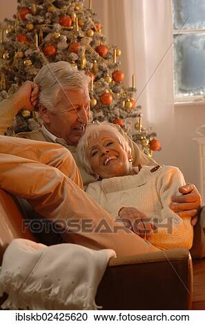 Mature couple in love lying on a sofa in front of a Christmas tree View Large Photo Image Stock Image - Mature couple in love lying on a sofa in front of a Christmas tree. Fotosearch