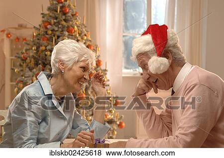 "Mature couple, man with a Santa hat, sitting in front of a Christmas tree" View Large Photo Image Stock Photo - "Mature couple, man with a Santa hat, sitting in front of a Christmas tree". Fotosearch