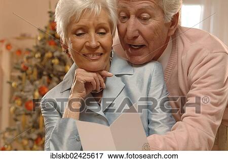 Mature couple reading Christmas cards in front of a Christmas tree View Large Photo Image Stock Photo - Mature couple reading Christmas cards in front of a Christmas tree. Fotosearch