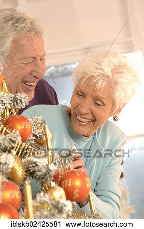 Mature couple smiling while decorating a Christmas tree View Large Photo Image Stock Image - Mature couple smiling while decorating a Christmas tree. Fotosearch