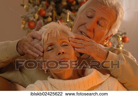 Mature man massaging a woman in front of a Christmas tree View Large Photo Image Stock Image - Mature man massaging a woman in front of a Christmas tree. Fotosearch