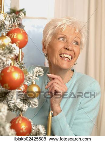 Stock Photo - Mature woman with a Christmas tree. Fotosearch