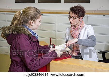 Picture - "Medical practice, the receptionist handing over a referral to specialist to a patient, Germany, Europe". Fotosearch