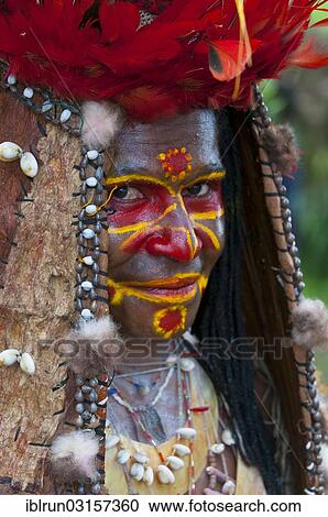 Stock Image - "Member of a tribe in a colourfully decorated costume with face paint is celebrating at the traditional Sing Sing gathering in the highlands, Paya, Papua New Guinea, Oceania". Fotosearch