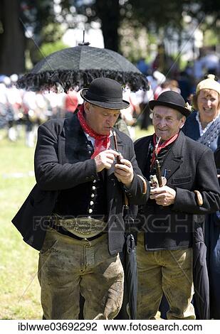 Stock Image - "Men wearing traditional costumes, smoking a pipe, Mondsee, Salzkammergut, Austria, Europe". Fotosearch