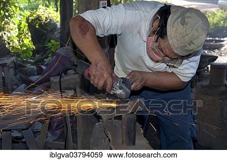 Stock Photo - "Metal worker grinding in a metalworking shop, Battambang, Cambodia, Asia". Fotosearch
