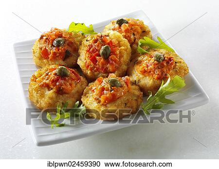 Stock Image - Mini potato roesti topped with tomato salsa and capers. Fotosearch
