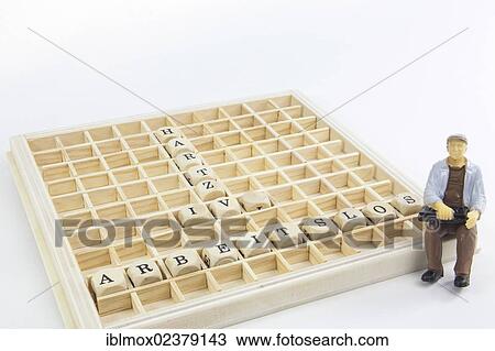 Stock Image - "Miniature figure of an unemployed worker, letter cubes forming the words """"arbeitslos"""" and """"Hartz IV"""", German for """"unemployed"""" and income support subsidies". Fotosearch
