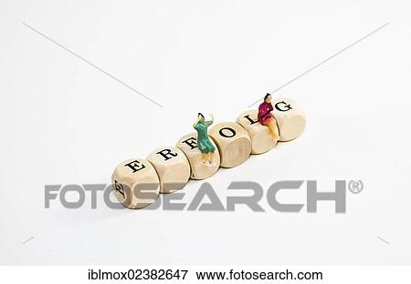 "Miniature figures sitting on wooden cubes with letters spelling the word Erfolg, German for success" View Large Photo Image Stock Photo - "Miniature figures sitting on wooden cubes with letters spelling the word Erfolg, German for success". Fotosearch