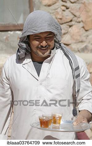 Stock Photo - "Modern Bedouin man carrying a tray with tea, Sinai Peninsula, Egypt, Africa". Fotosearch