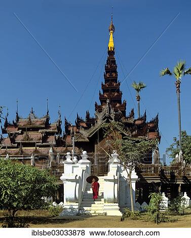 Stock Photo - "Monk on the stairs outside a building made of teak, Shwe In Bin Kyaung Monastery, Mandalay, Mandalay Division, Myanmar, Burma, Asia". Fotosearch