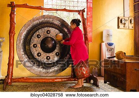 Stock Photo - "Monk using a Gong during the prayer, Wat Si Muang, Vientiane, Vientiane Prefecture, Laos, Asia". Fotosearch