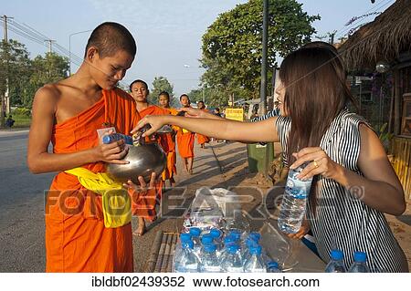 "Morning alms round, a young Buddhist monk from a monastery school holding a begging bowl, receiving and offerings from a young woman, Sukhothai Province, Northern Thailand, Thailand, Asia" View Large Photo Image Stock Image - "Morning alms round, a young Buddhist monk from a monastery school holding a begging bowl, receiving and offerings from a young woman, Sukhothai Province, Northern Thailand, Thailand, Asia". Fotosearch