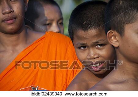Stock Image - "Morning alms round, smiling young Buddhist monk from the monastery school, portrait, Sukhothai Province, Northern Thailand, Thailand, Asia". Fotosearch