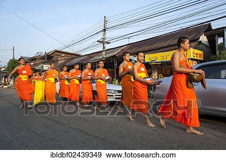 Stock Photo - "Morning alms round, young Buddhist monks from a monastery school holding begging bowls, Sukhothai Province, Northern Thailand, Thailand, Asia". Fotosearch