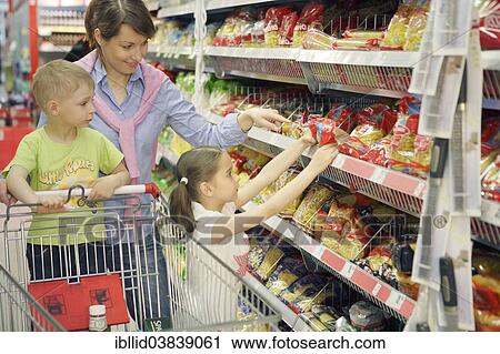Stock Image - "Mother and children shopping for food, woman 35 years, girl 7 years and a boy 5 years". Fotosearch