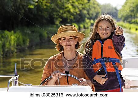 "Mother and daughter at the wheel of a Penichette, houseboat on the Canal de Pont-de-Vaux, Pont-de-Vaux, Pont-de-Vaux, Region Rhone-Alpes, Dep. Ain, France, Europe" View Large Photo Image Stock Photograph - "Mother and daughter at the wheel of a Penichette, houseboat on the Canal de Pont-de-Vaux, Pont-de-Vaux, Pont-de-Vaux, Region Rhone-Alpes, Dep. Ain, France, Europe". Fotosearch