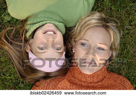 Stock Photo - Mother and daughter lying head to head on the grass. Fotosearch